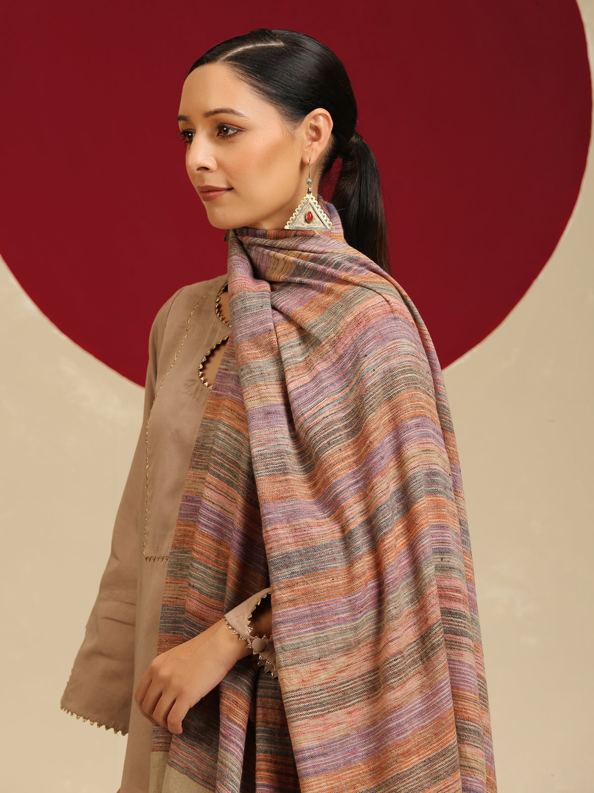 Model is wearing a Pashmina Stripe Stole featuring multicolour stripes on a light gray base. 