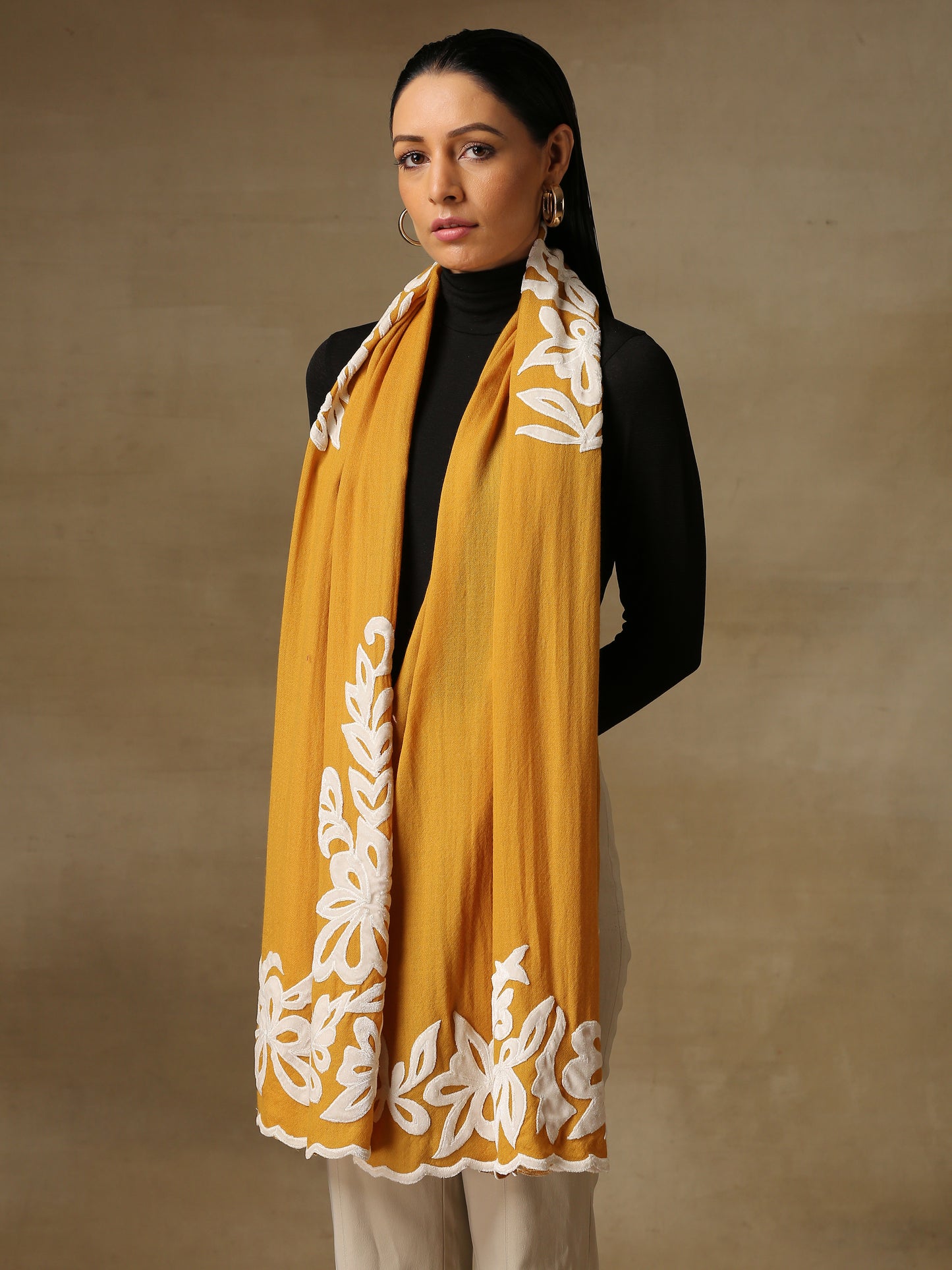 Model is wearing a Velvet Affair stole from Shaza featuring white velvet applique on a mustard coloured cashmere stole. 