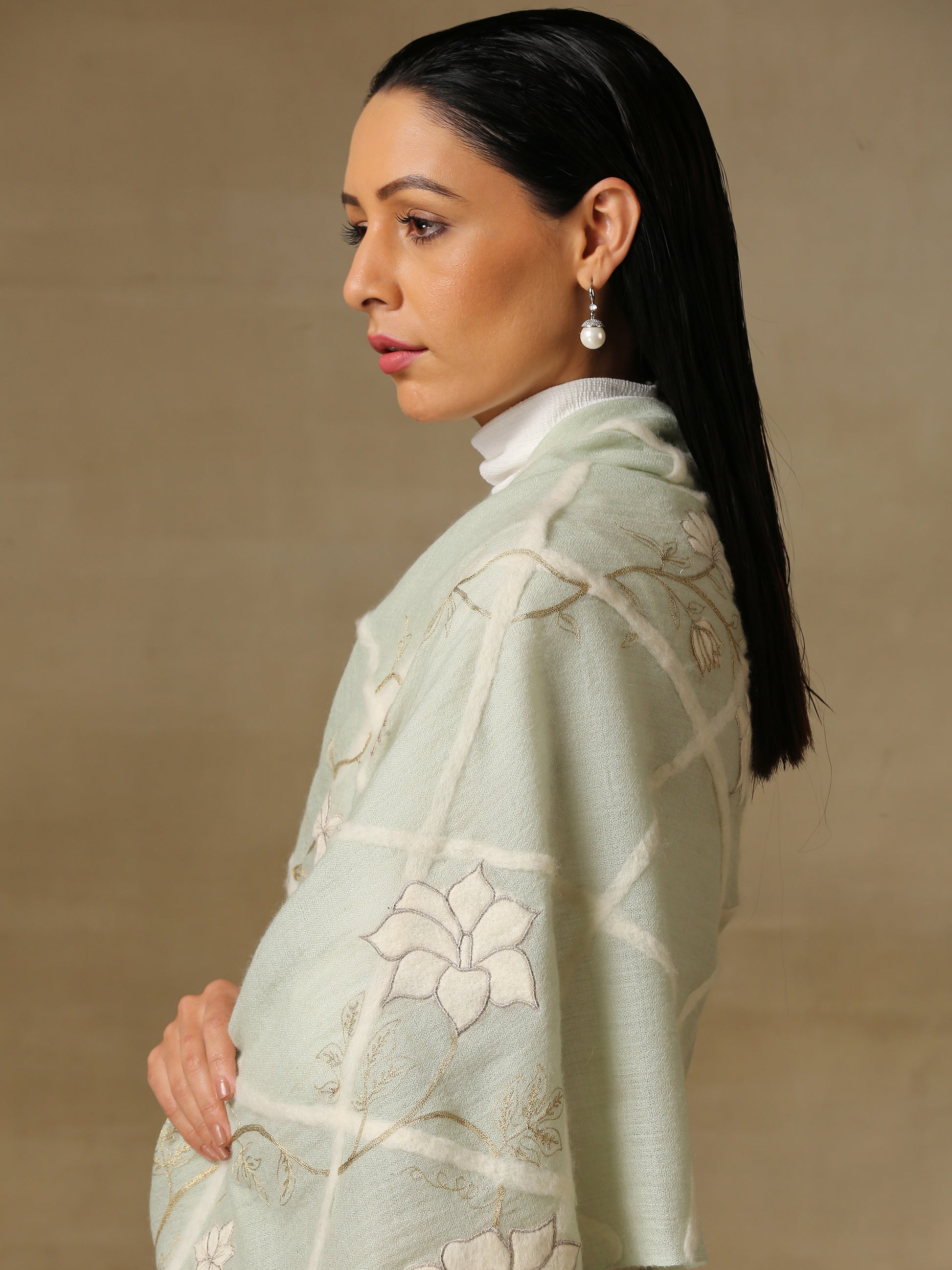 Model is wearing the Daisy pashmina stole in mint green from Shaza, featuring threadwork of interwoven lines, applique of daisy figures and zari work on handloomed pashmina. 