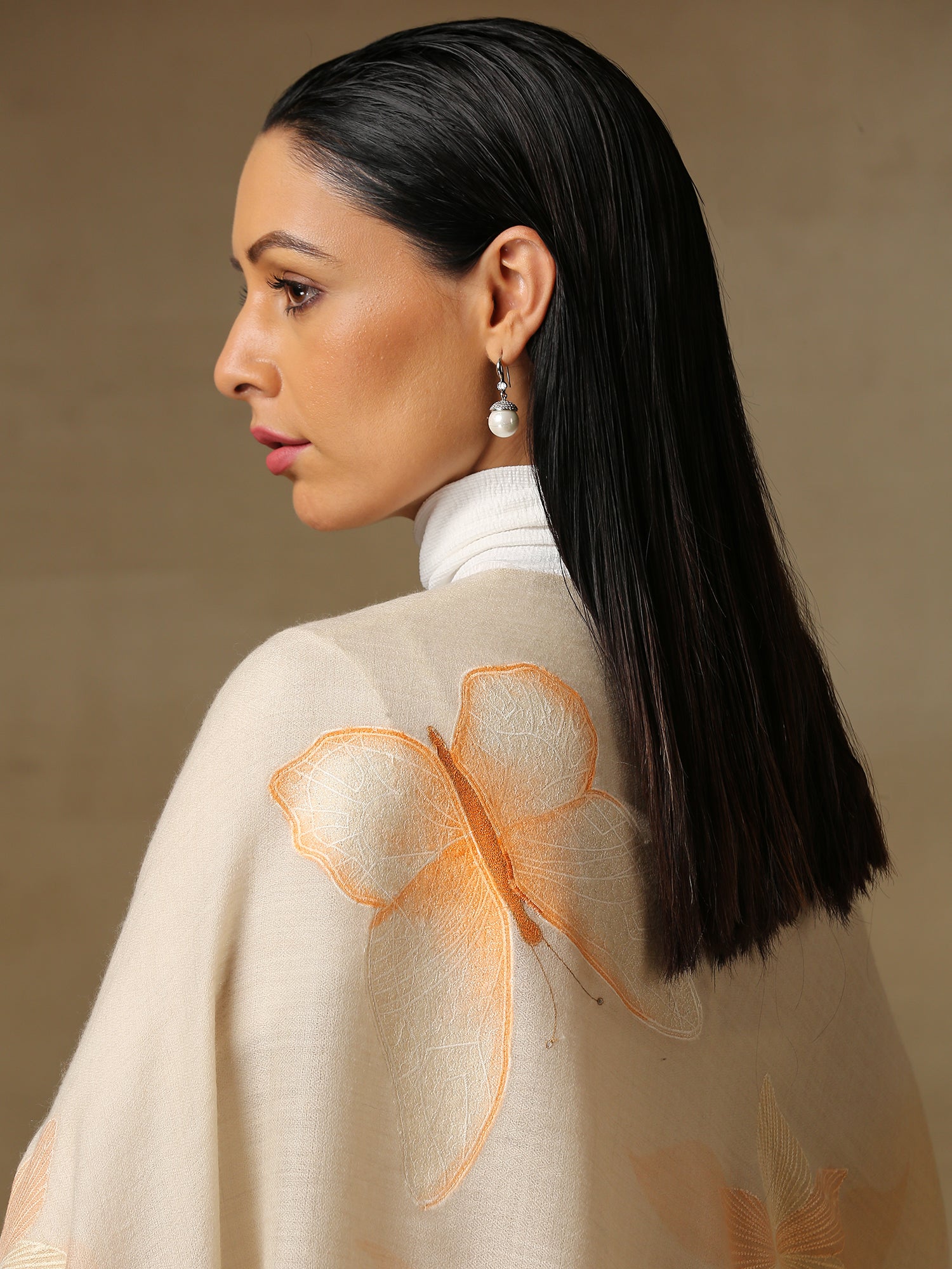 Model is wearing the butterfly pashmina stole from Shaza, featuring hand embroidered butterfly shapes decorated with swarovski on a cream pashmina stole. 