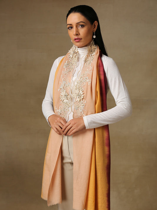 Model is wearing an Elements of Spring pashmina stole by Shaza, featuring applique or chantilly, decorated with delicate threadwork and pearl embroidery on a pashmina stole in an ombre of pink, orange and wine colours. .
