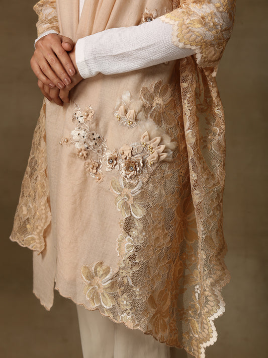 Model is wearing a pashmina stole in a peachy nude are lavishly embellished with floral motifs, made with threadwork, swarovski, pearls, and applique. This stole is from the Elements of spring collection.  