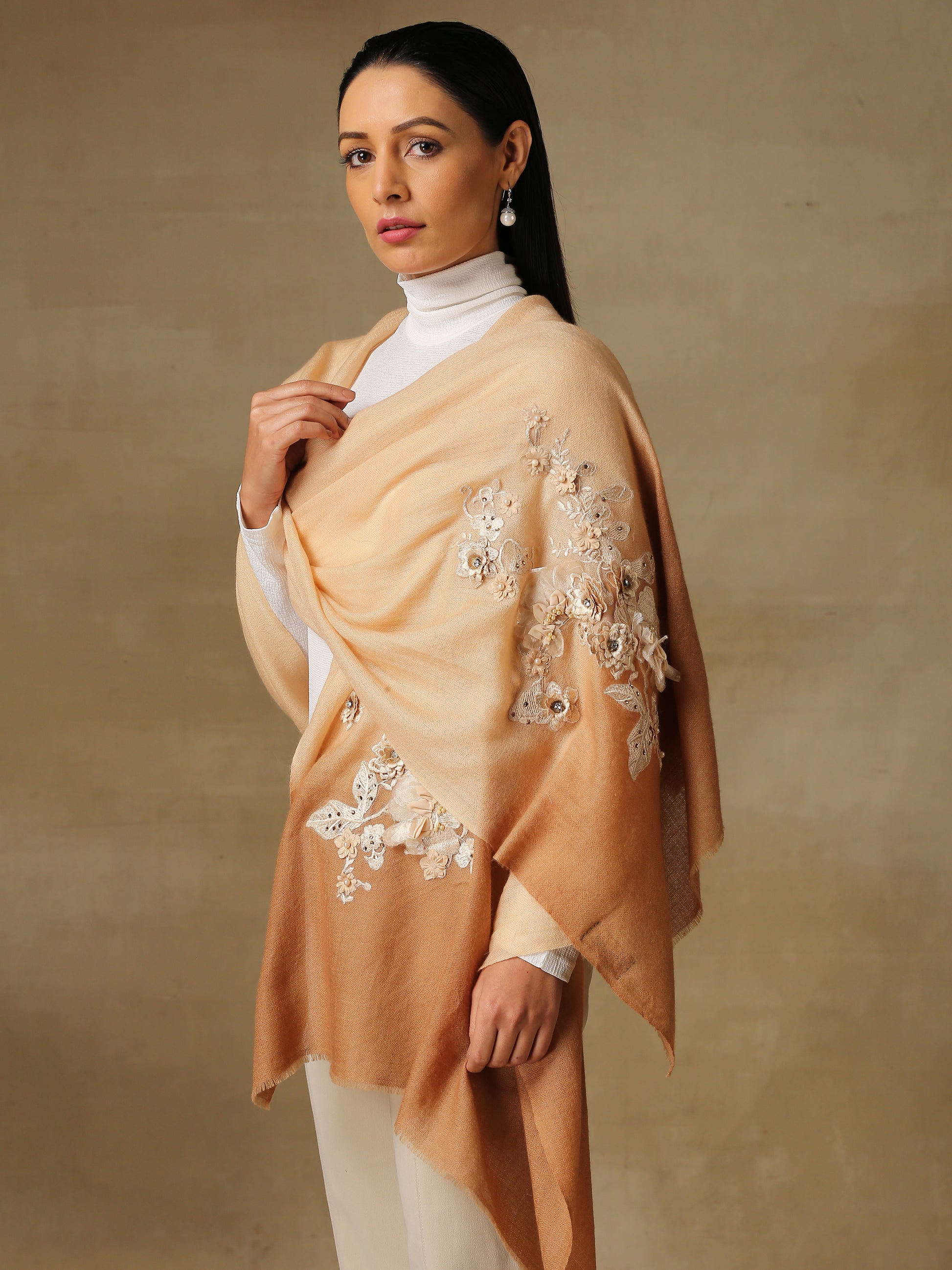 Model is wearing a pashmina stole in an ombre of nude and brown is lavishly embellished with floral motifs, made with threadwork, swarovski, pearls, and applique. This stole is from the Elements of spring collection.  