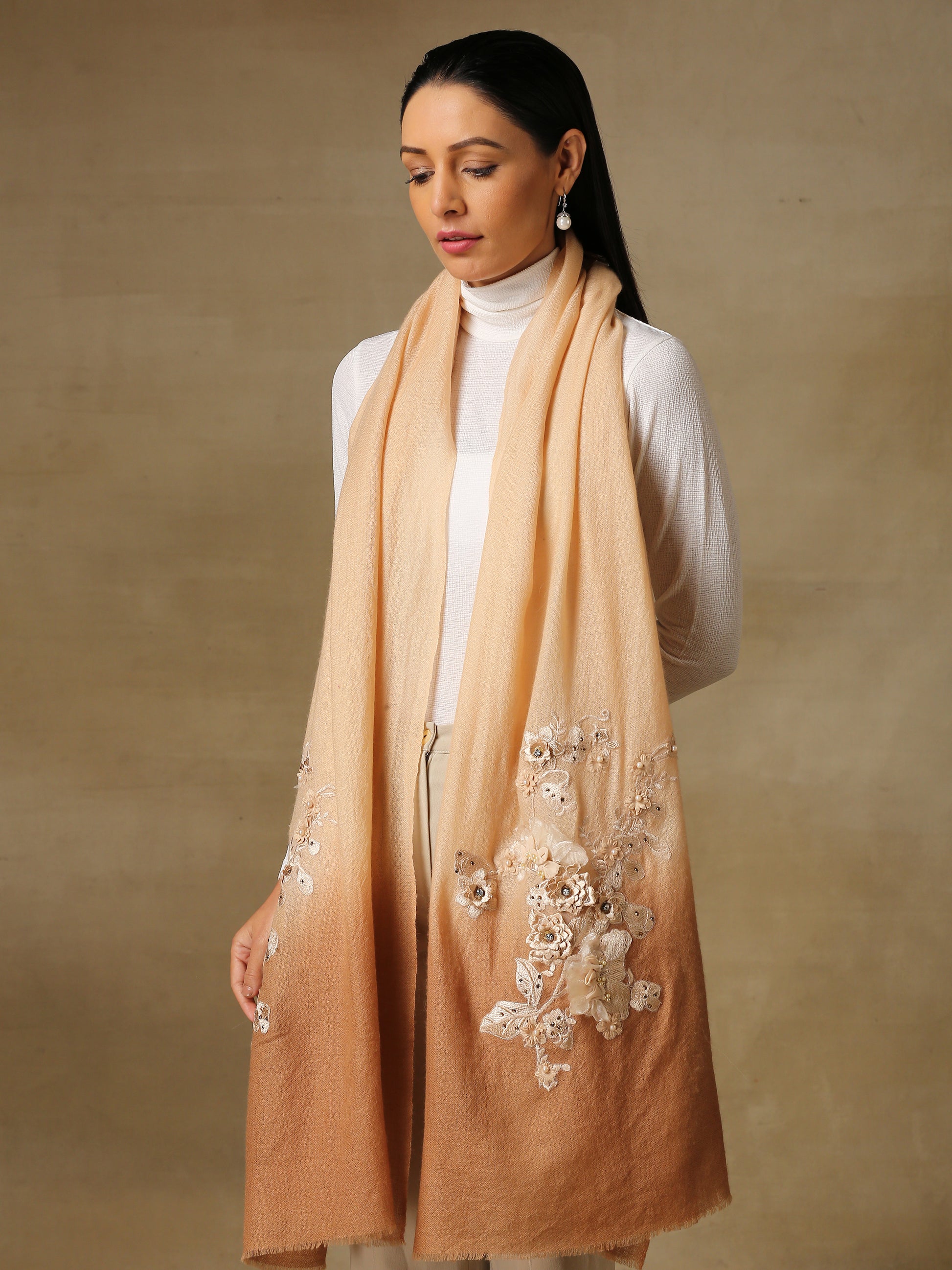 Model is wearing a pashmina stole in an ombre of nude and brown is lavishly embellished with floral motifs, made with threadwork, swarovski, pearls, and applique. This stole is from the Elements of spring collection.  