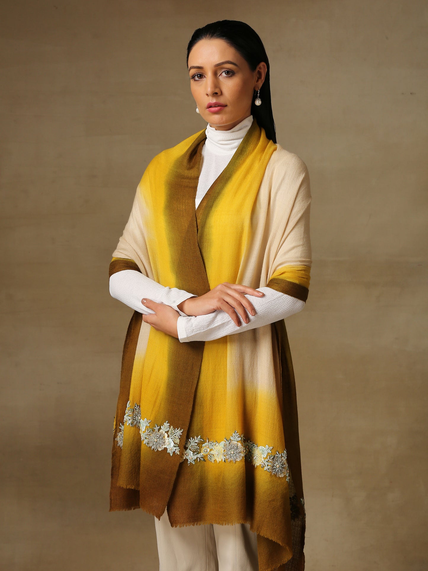 Model is wearing Enchanted pashmina stole from shaza in senescence featuring a hand painted ombre in ochre colours and delicate embroidery consisting of pearls, shellwork and cutdana. 