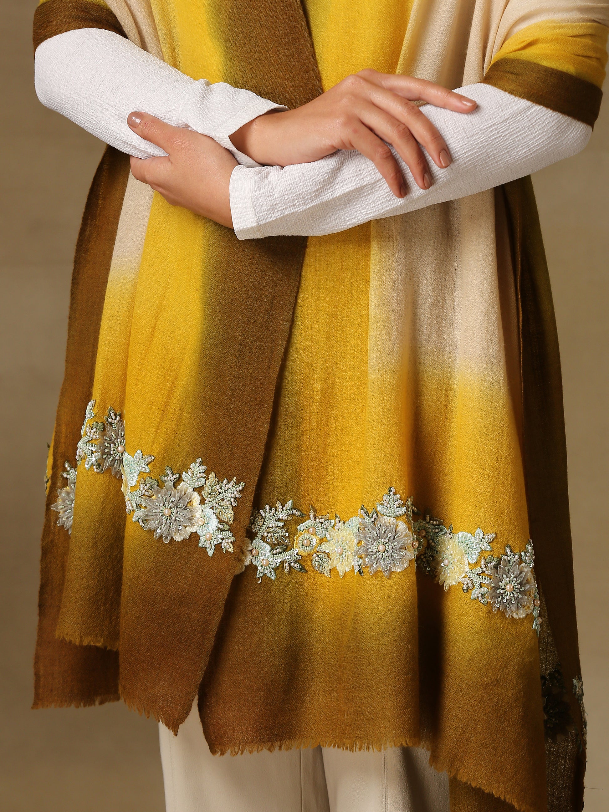 Model is wearing Enchanted pashmina stole from shaza in senescence featuring a hand painted ombre in ochre colours and delicate embroidery consisting of pearls, shellwork and cutdana. 