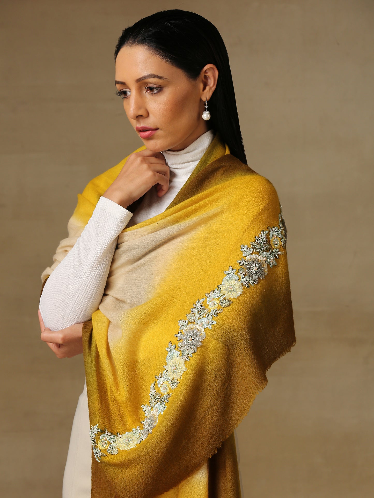 Model is wearing Enchanted pashmina stole from shaza in senescence featuring a hand painted ombre in ochre colours and delicate embroidery consisting of pearls, shellwork and cutdana. 