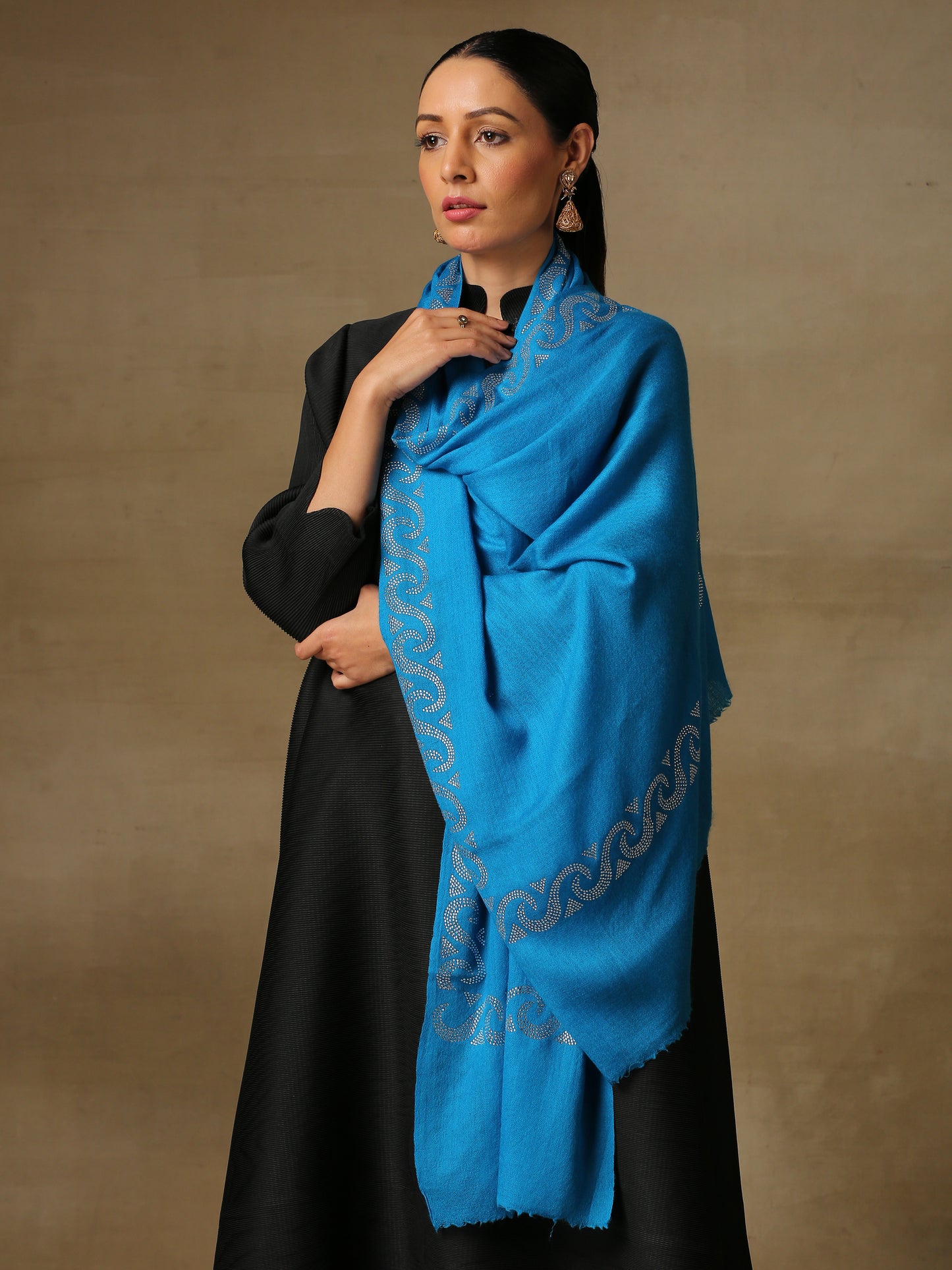 Model is wearing a firozi blue stole from the Era of Zaywar Border Swarovski Stole collection, hand embellished with fine silver swarovski in a waves design